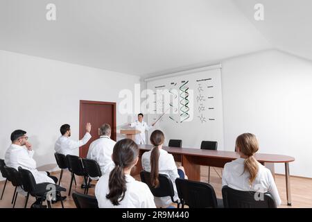 Lecture about difference between RNA and DNA. Professor using projection screen with illustration to audience in conference room Stock Photo