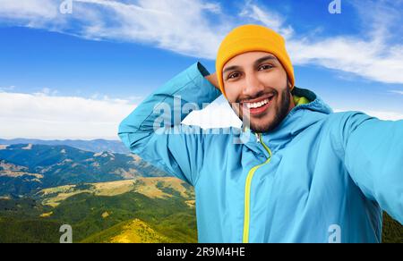 Smiling young man taking selfie in mountains Stock Photo