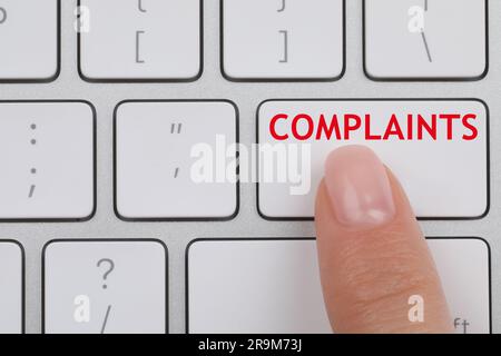 Woman pressing button with word Complaints on computer keyboard, top view Stock Photo