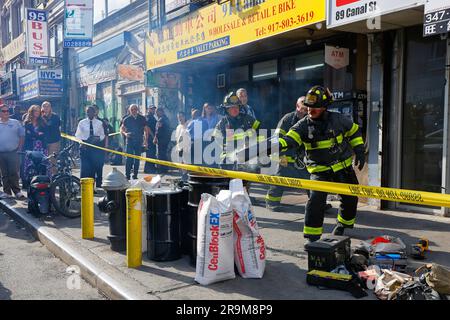 New York, USA, June 27, 2023, FDNY fire officials inspect an e-bike repair shop in Manhattan Chinatown in search of defective and unsafe Li-ion batteries. Pictured: NYC Fire Commissioner Laura Kavanagh and other city officials (left) watch as firefighters dispose of a lithium ion electric bike battery that was accidentally punctured during disposal causing a short circuit and fire. Recent deaths from the June 20th fire at an e bike shop on Madison St--on top of multiple other fires this year blamed on electric bike batteries across the city--has spurred the city toward increased enforcement. Stock Photo