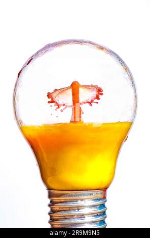 Orange juice drop impact in light bulb Stock Photo