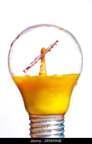 Orange juice drop impact in light bulb Stock Photo