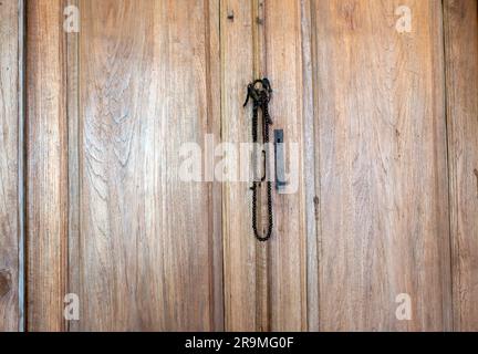 Prayer beads hanging on a vintage teak wood wall in a mosque. Islamic wallpaper. Stock Photo