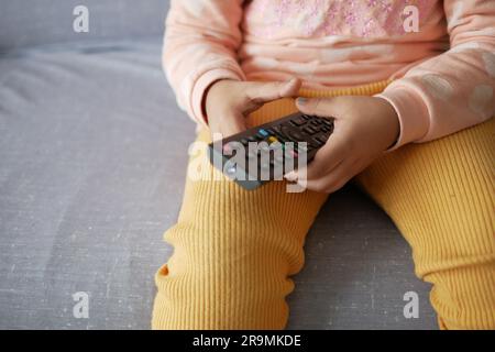 child holding tv remote while sitting on sofa  Stock Photo