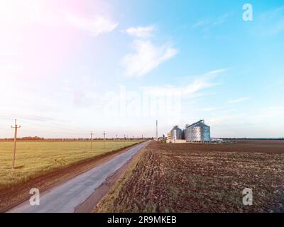 Modern metal silos on agro-processing and manufacturing plant. Aerial view of Granary elevator processing drying cleaning and storage of agricultural Stock Photo