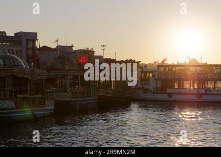 Fish sandwich (Balık ekmek) boats & passenger ferry on the Golden Horn River at a summers sunset iin Eminonu, Istanbul, Turkey. Stock Photo