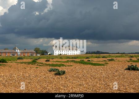 Dark rain clouds over houses and beach at Shingle Street, Suffolk, England, UK Stock Photo