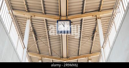 Roofing of the railway station made of trapezoidal sheet. Steel construction. Blue clock on the platform Stock Photo