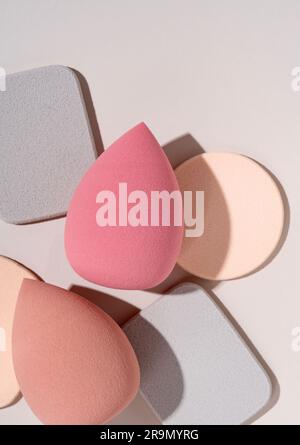 Multiple egg-shaped makeup sponges placed on a beige background. View from above. Stock Photo