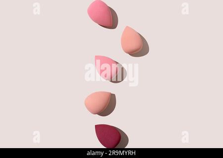Multiple egg-shaped makeup sponges placed on a beige background. View from above. Stock Photo