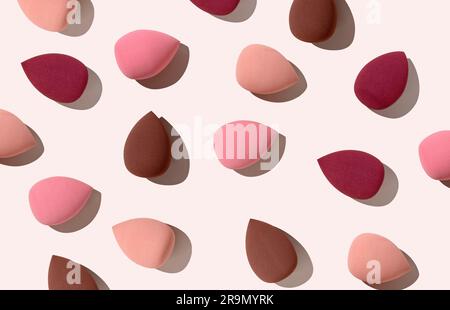 Multiple egg-shaped makeup sponges placed on a beige background. View from above. Stock Photo