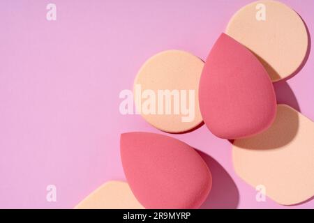 Multiple egg-shaped makeup sponges placed on a pink background. View from above. Stock Photo