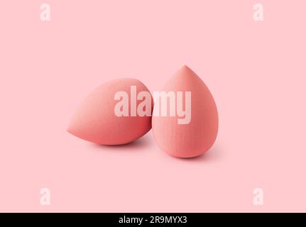Multiple egg-shaped makeup sponges placed on a pink background. Stock Photo