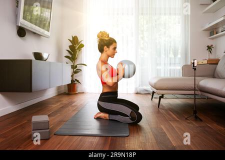 fitness online instructor teaching virtual class with exercise ball at home Stock Photo