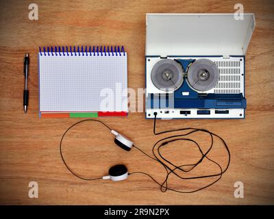 Reel tape recorder with headphones and blank notepad on wooden table. View from above Stock Photo