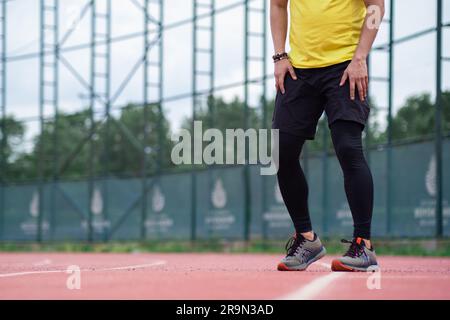 Sportsman in leggings and shorts training on running track on urban sports arena closeup Stock Photo