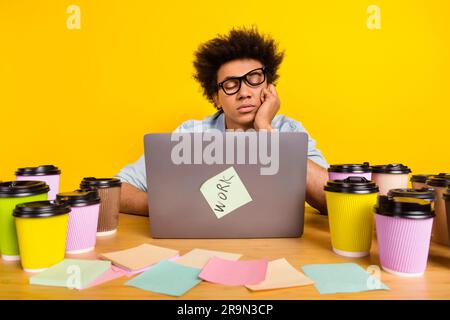 Photo of sleepy tired guy closed eyes desktop netbook coffee cup isolated on yellow color background Stock Photo