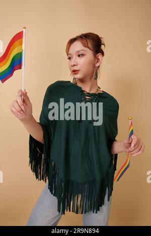 Young transgender woman posing with two rainbow flags, pride month concept Stock Photo