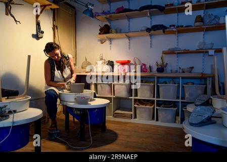 young ceramist woman hands working and shaping clay on the lathe or potter's wheel inside a pottery workshop Stock Photo