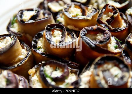 delectable eggplant rolls Parmesan. This appetizer features grilled eggplant rolls stuffed with creamy feta cheese, beautifully presented on a rustic Stock Photo