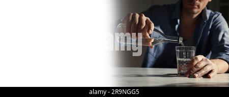 Suffering from hangover. Man pouring alcoholic drink into glass at table indoors, closeup. Banner design with space for text Stock Photo