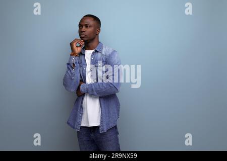 portrait of young smart inspired with dark skin american guy dressed stylishly in casual clothes on blue background with copy space Stock Photo