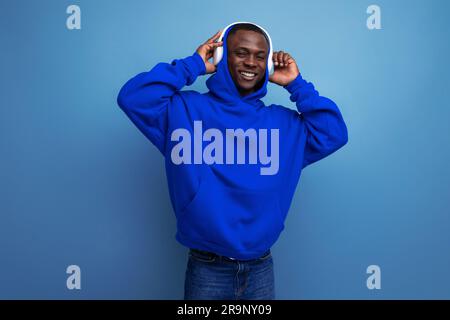 cool energetic dark-skinned american man with modern wireless headphones on the background with copy space Stock Photo