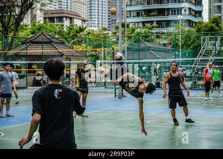 A Thai player of Sepak Takraw is seen performing an acrobatic figure during a game at Benchasiri Public Park on Sukhumvit Road. Sepak Takraw also called kick volleyball or Thailand’s Acrobatic Volleyball is one of Southeast Asia’s most popular sports which is played with a ball made of rattan or synthetic plastic where the players are only allowed to touch the ball with their feet, body, or head. Stock Photo