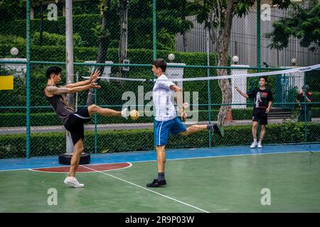 Thai and foreign players of Sepak Takraw are seen playing a game at Benchasiri Public Park on Sukhumvit Road. Sepak Takraw also called kick volleyball or Thailand’s Acrobatic Volleyball is one of Southeast Asia’s most popular sports which is played with a ball made of rattan or synthetic plastic where the players are only allowed to touch the ball with their feet, body, or head. Stock Photo