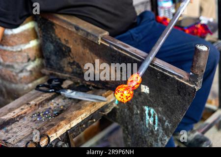 Craftsman working, cutting and molding the glass with the traditional ...