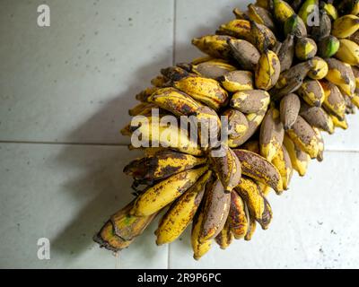 Unhealthy, mottled bunch of ripe bananas on the white floor Stock Photo