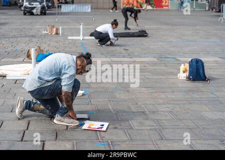 Kaiserslautern, Germany. 28th June, 2023. Three international artists at the very beginning of their work. Eleven international artists from 6 countries are turning the Stiftsplatz (Square) pavement into three-dimensional art. 3D street art uses perspective to create optical illusion of space. Visitors are welcome to watch all artists at work over three days from Wednesday at 8:00 AM to Friday 6:00 PM. This years topic is 'Digitalisation and Smart City'. Paintings will depict robots, data, or cyberpunk scenarios. Credit: Gustav Zygmund/Alamy News Stock Photo