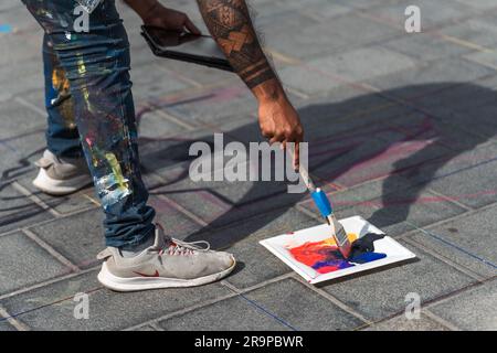 Kaiserslautern, Germany. 28th June, 2023. Artist at work, using brush and colourful paint. Eleven international artists from 6 countries are turning the Stiftsplatz (Square) pavement into three-dimensional art. 3D street art uses perspective to create optical illusion of space. Visitors are welcome to watch all artists at work over three days from Wednesday at 8:00 AM to Friday 6:00 PM. This years topic is 'Digitalisation and Smart City'. Paintings will depict robots, data, or cyberpunk scenarios. Credit: Gustav Zygmund/Alamy News Stock Photo