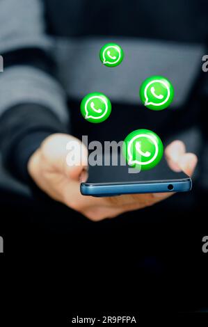 holding a mobile phone and whats app symbols over it Stock Photo