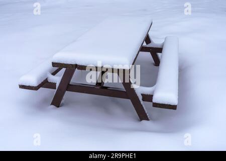 Snow covered wooden picnic table in winter. Stock Photo