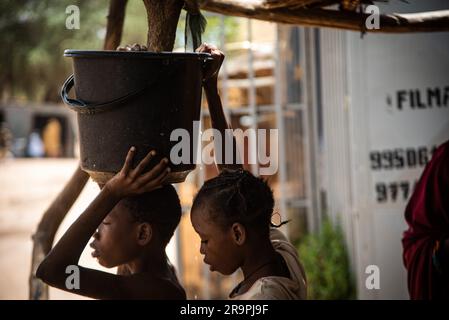 Nicolas Remene/Le Pictorium - Access to drinking water and standpipes in Niamey, Niger. , . Niger/Niamey/Niamey - Two young children are fetching water. One of them is carrying a bucket on his head which he has just filled at a standpipe. He paid 10F CFA for a 10l bucket. The girl behind him helps him hold the bucket on his head to take it back to his house. They repeated this operation several times during the morning in the terrible heat, in Niamey, Niger on 28 April 2020. In Niamey, Niger, during the hot seas Credit: LE PICTORIUM/Alamy Live News Stock Photo