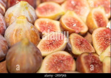 Sliced and halved figs on a cutting board next to a row of whole figs. Stock Photo