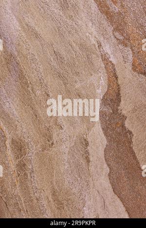 Beautiful velvety brown veined granite. Granite surface for external exterior decoration of the house. Vertical image. Stock Photo