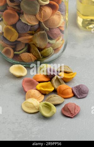 Colorful Italian raw Orecchiette Arcobaleno pasta, rainbow pasta, in a glass bowl close up Stock Photo