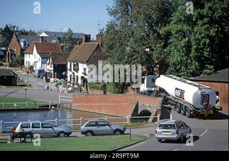 Archival 1994 image of Elf Aquitaine brand and logo on side and back rear end of fuel delivery tanker semi articulated trailer pulled along by hgv lorry truck power unit maneuvering across narrow hump back road bridge in village landscape at Finchingfield in Essex including village pond and car parking in this popular English picture postcard type of visitor attraction in England UK Stock Photo