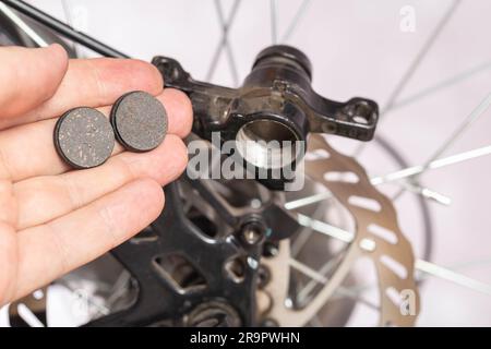 new brake pads in hand on the background of a bicycle brake caliper. Replacement of brake pads Stock Photo