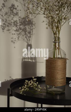 Close-up shot of a rustic ceramic vase filled with dried natural plants sitting on a wooden table Stock Photo