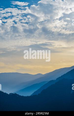 Sunset in the mountains. Dramatic colorful clouds over blue hills Stock Photo