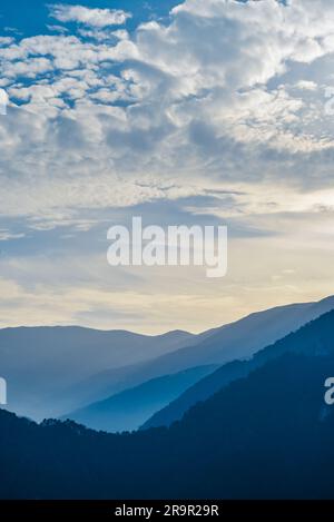 Sunset in the mountains. Dramatic colorful clouds over blue hills Stock Photo