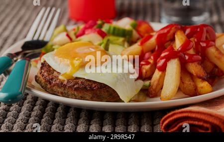 Pub lunch of fries,beef burger topped with fried egg and salad. Stock Photo