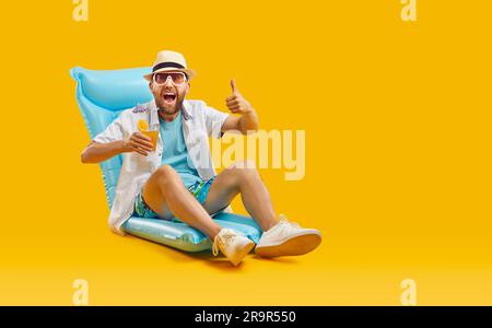 Happy man having summer vacation, sitting on beach, drinking cocktail and showing thumbs u Stock Photo