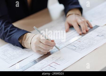 Closeup engineer at workstation drawing blueprints and plans by hand holding ruler Stock Photo
