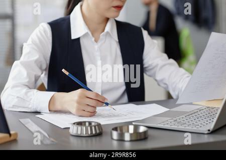 Closeup of female engineer using computer at workplace in office and designing blueprints Stock Photo