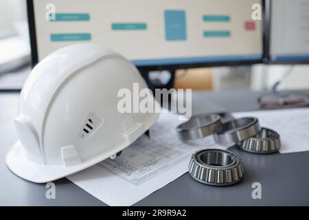 Closeup background image of steel ball bearings and machine parts on engineers workplace with hardhat, copy space Stock Photo