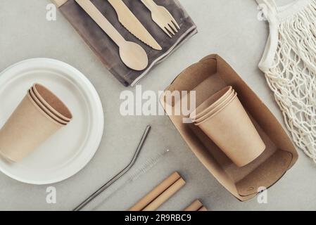 Set of eco-friendly tableware and kraft paper food packaging on light concrete background. Street food paper packaging - cups, plates, straws, contain Stock Photo